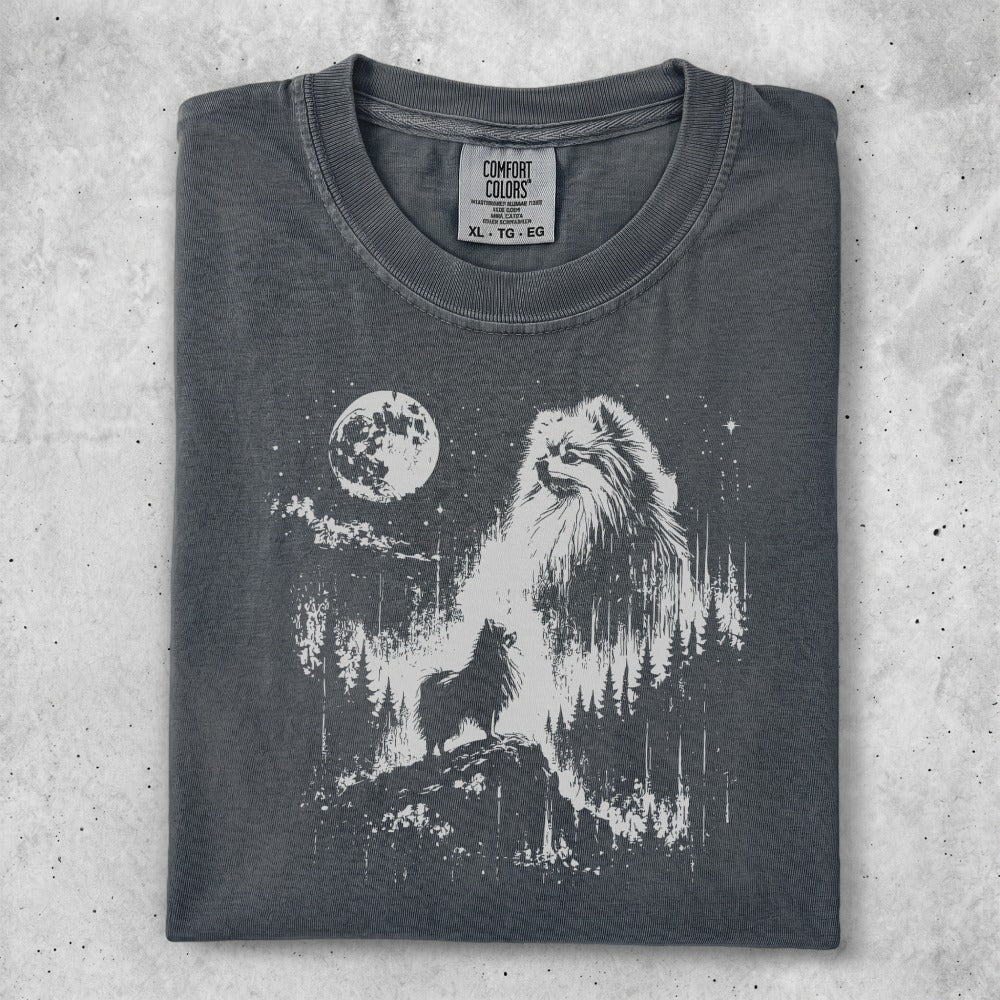 Dark grey t-shirt with white graphic of a Pomeranian dog on a rocky outcrop overlooking a forest and moonlit sky.