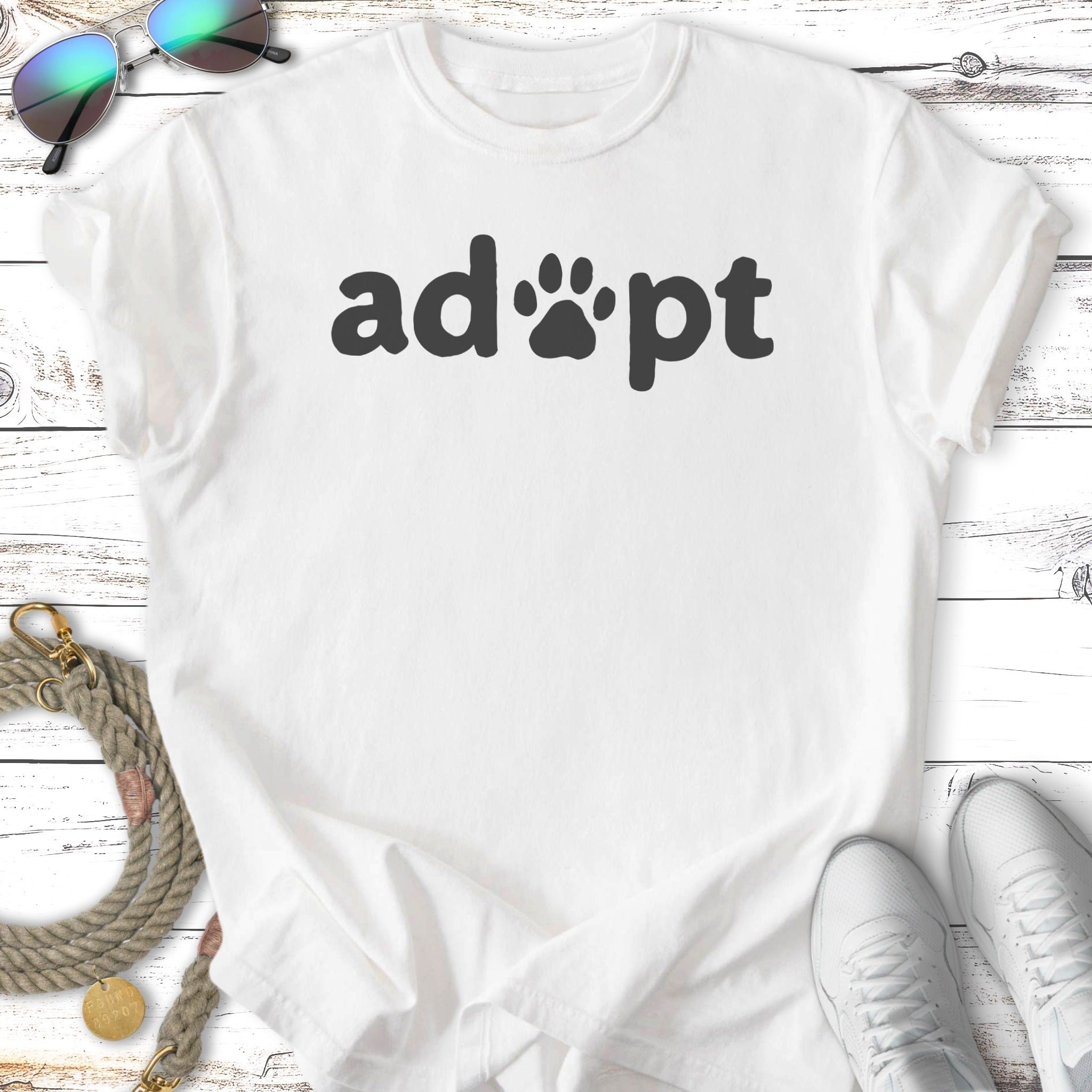 White t-shirt with "adopt" text and paw print.