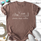 Brown t-shirt with "plants. dogs. coffee." in white cursive, surrounded by line art.