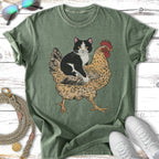 Green t-shirt with black and white cat riding a chicken graphic.