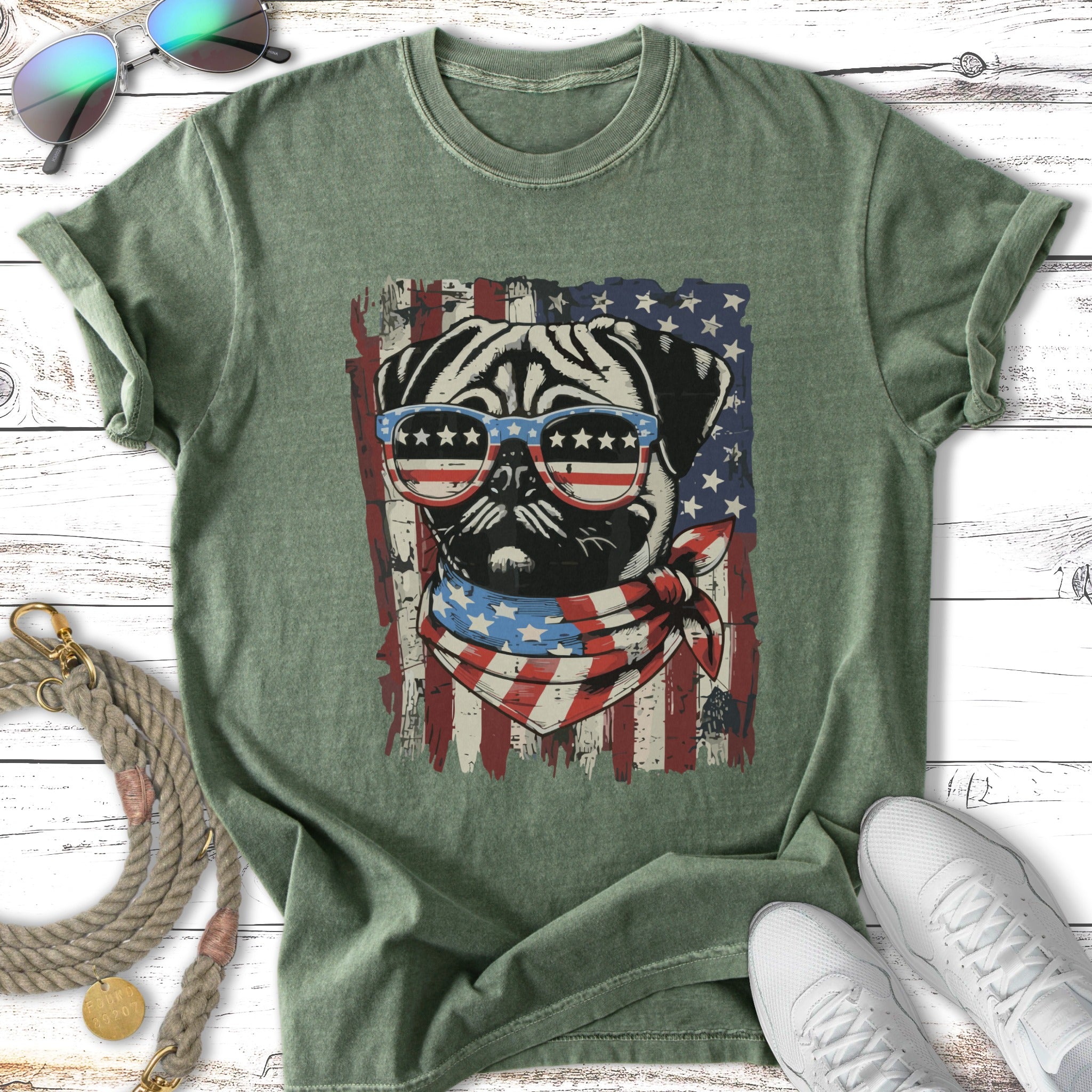 Pug wearing American flag sunglasses and bandana on green t-shirt.