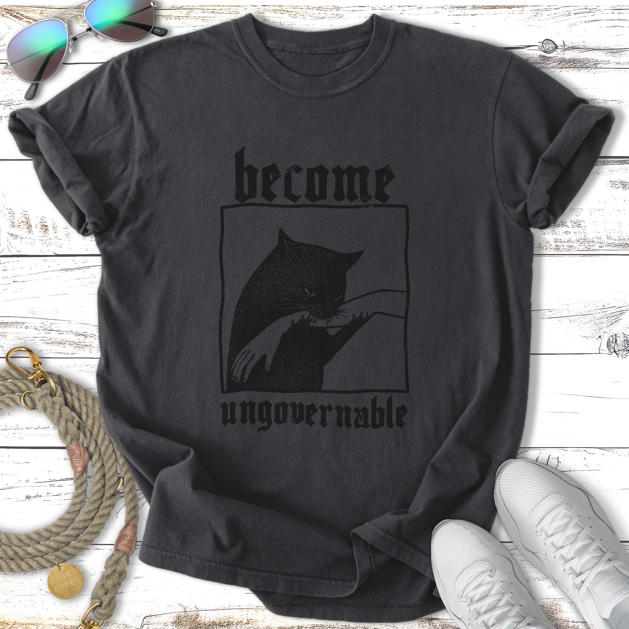 Dark t-shirt with "become ungovernable" text and a distressed cat illustration.