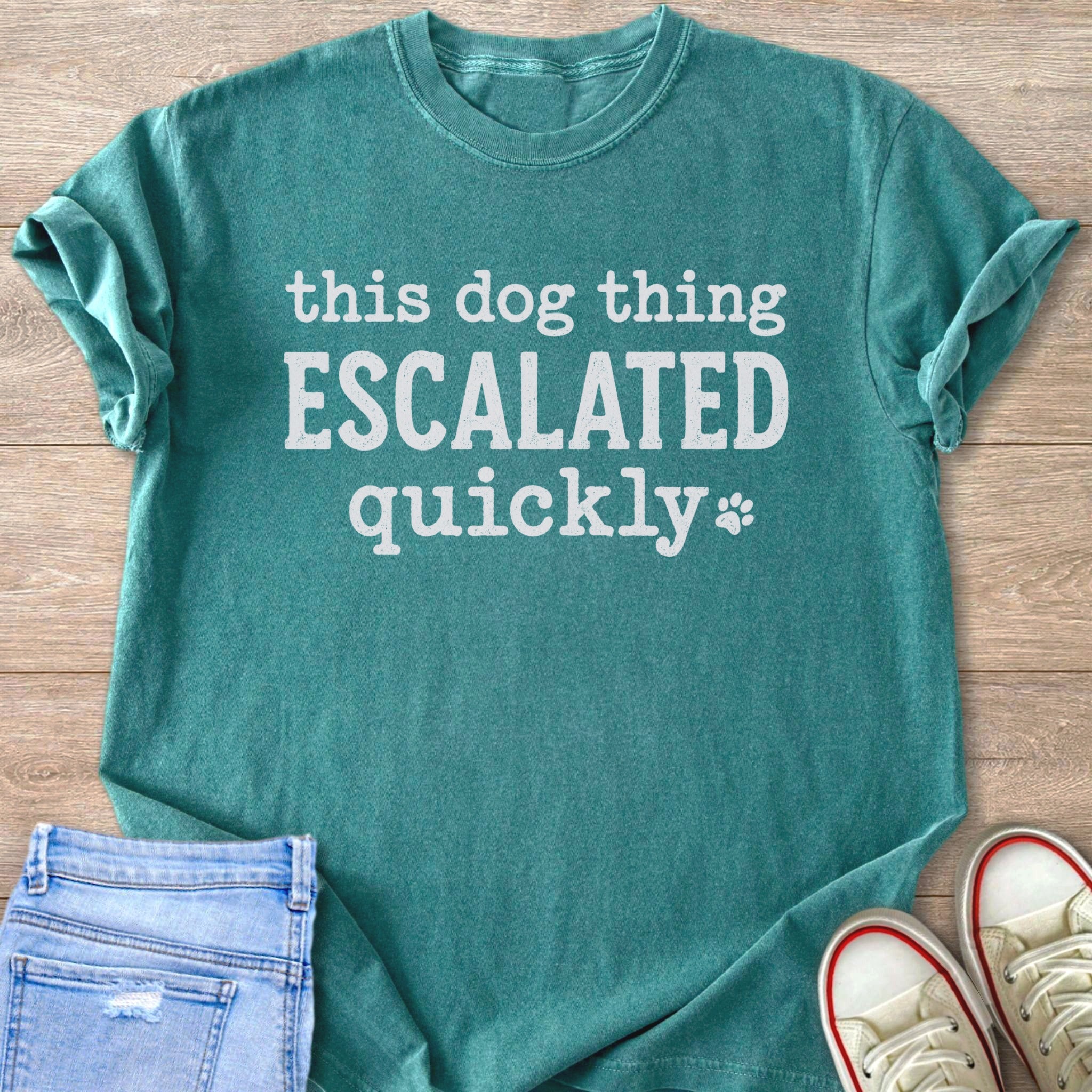Teal t-shirt with white text "this dog thing ESCALATED quickly" and a paw print.