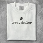 White t-shirt with "treat dealer" and a paw print graphic.