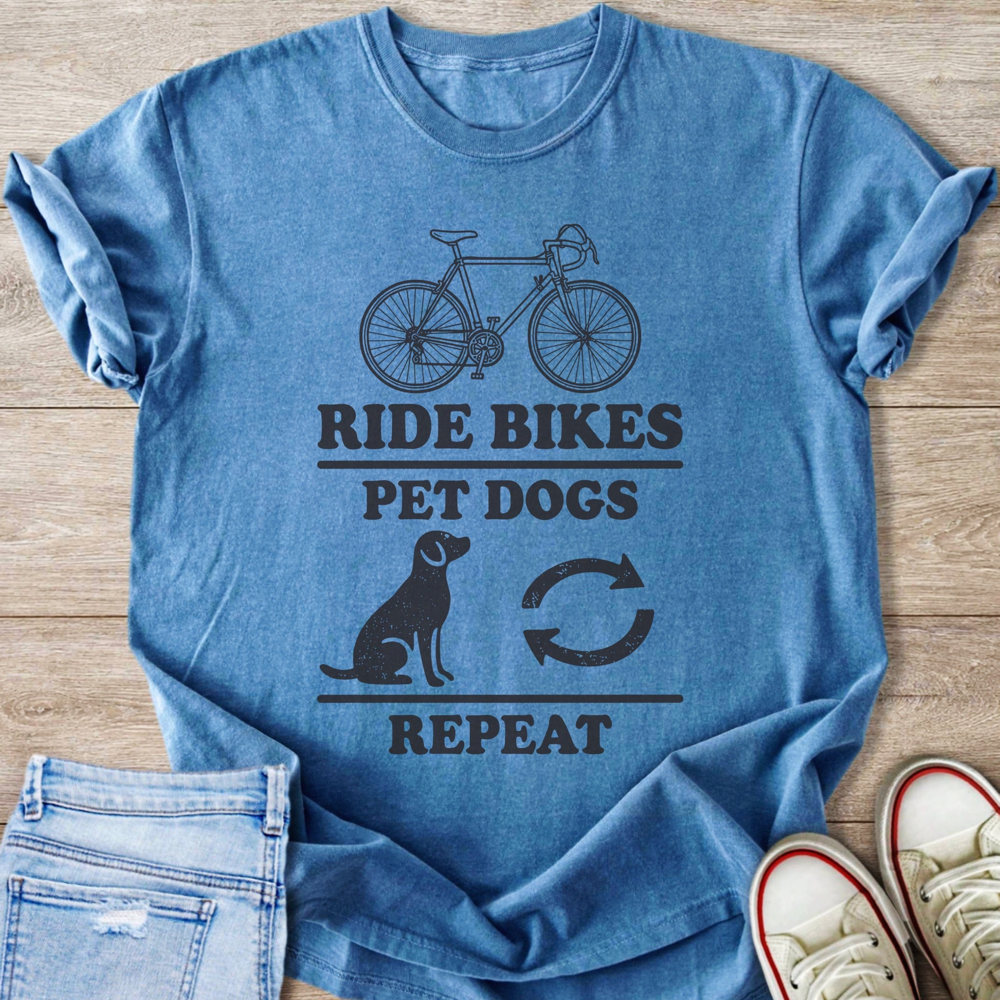 Blue t-shirt with "Ride Bikes Pet Dogs Repeat" graphic and icons.