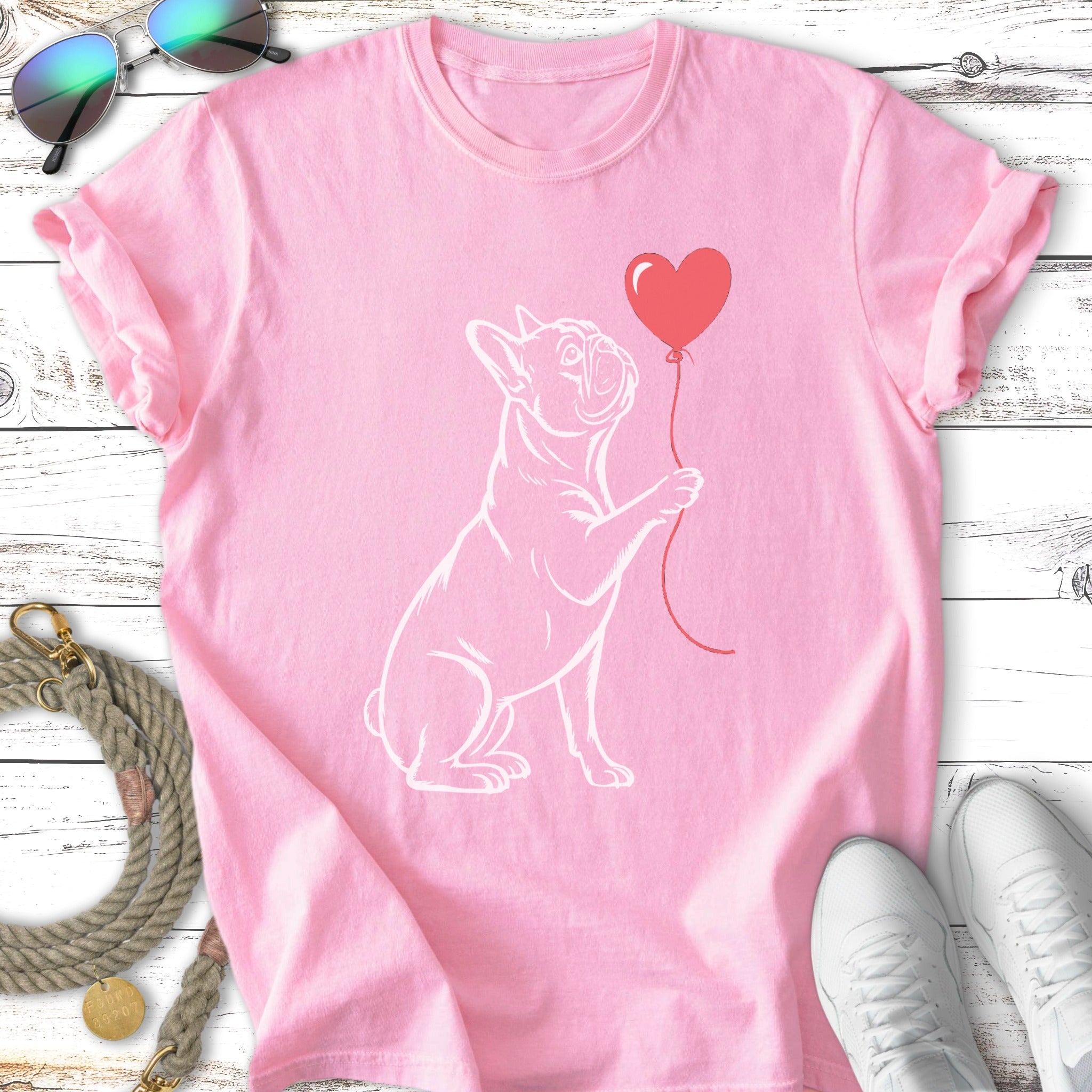 Pink t-shirt with a white outline of a French bulldog holding a red heart balloon.