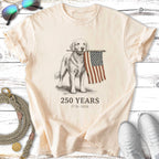 Golden retriever holding an American flag, with text "250 YEARS 1776-2026".