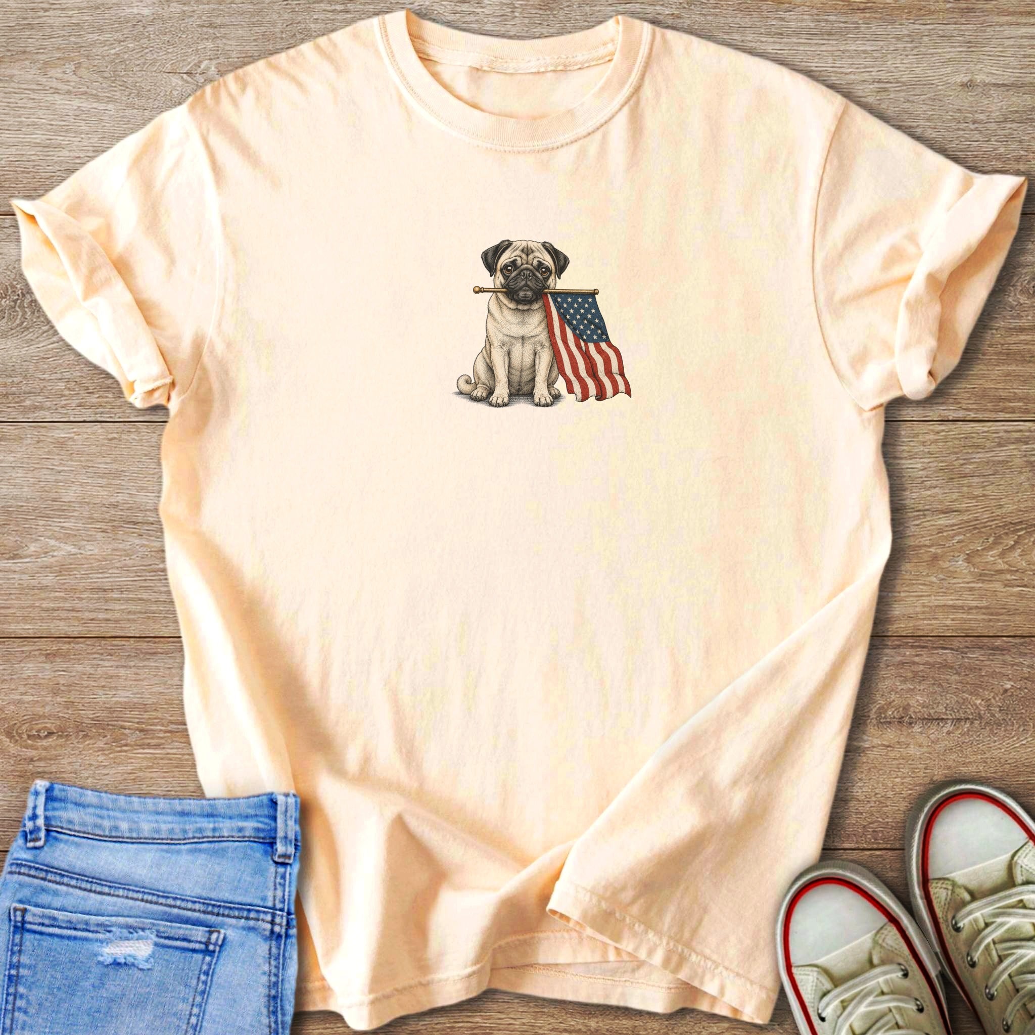 Light yellow t-shirt with a drawing of a pug holding an American flag in its mouth.