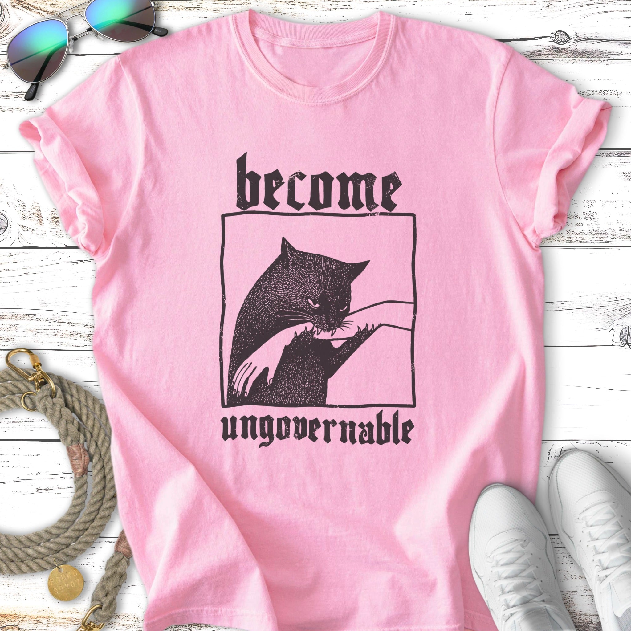 Pink t-shirt with black graphic of a cat and text "become ungovernable".