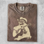 T-shirt with distressed tan graphic of a pug wearing a cowboy hat, playing guitar.