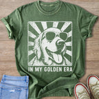 Green t-shirt with retro distressed graphic of a golden retriever wearing sunglasses and text "IN MY GOLDEN ERA."