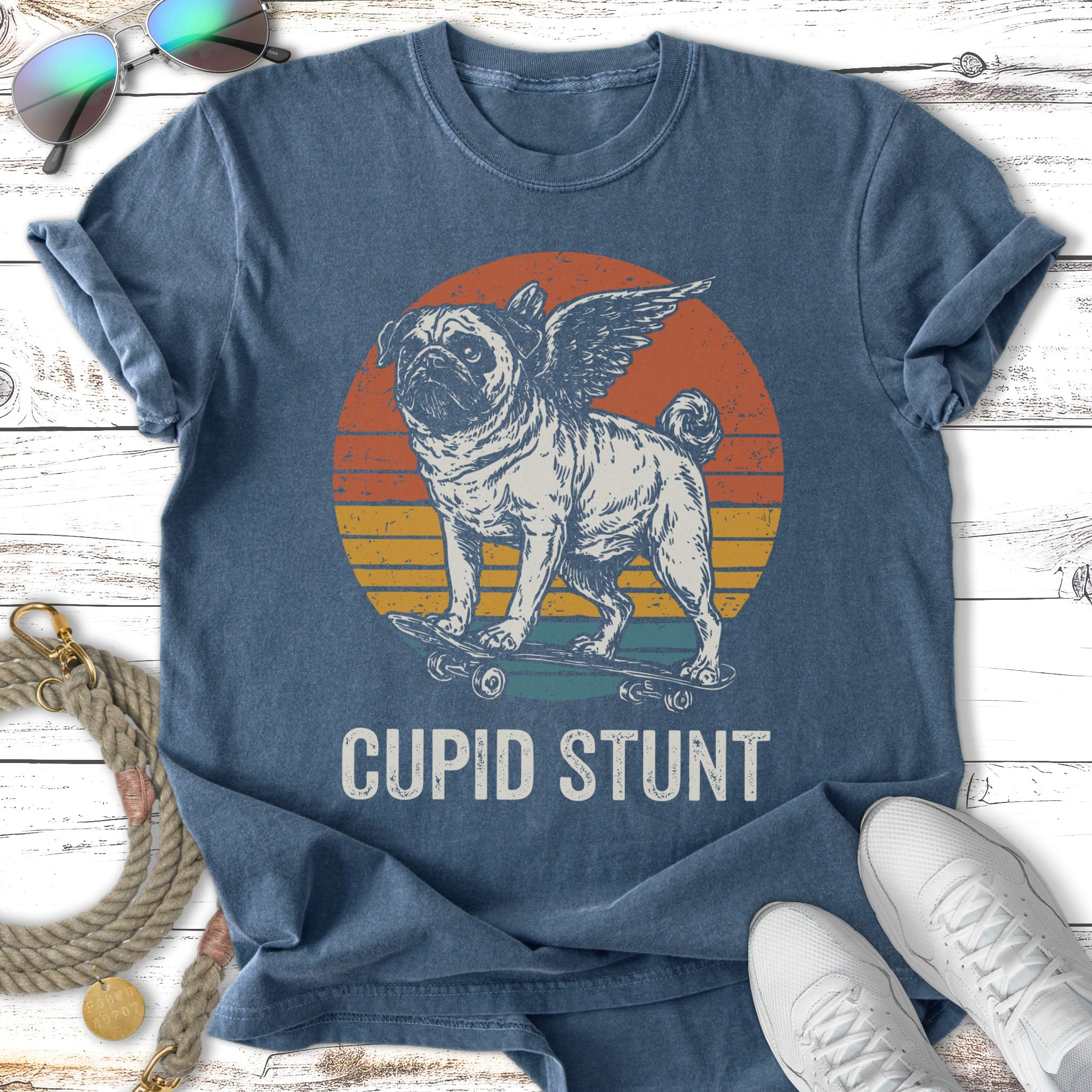 Pug with wings on a skateboard against a sunset, text "Cupid Stunt".