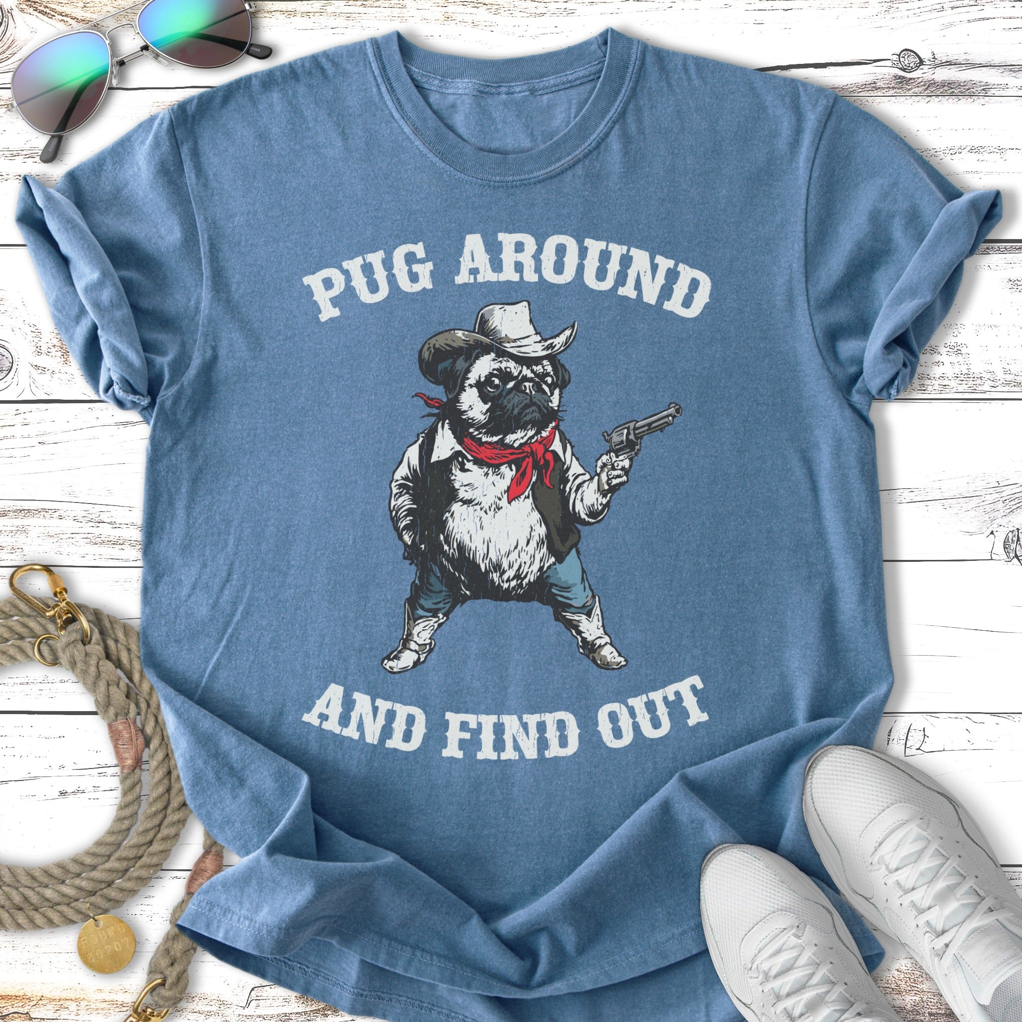 Blue t-shirt with pug in cowboy outfit holding a gun, text "PUG AROUND AND FIND OUT".