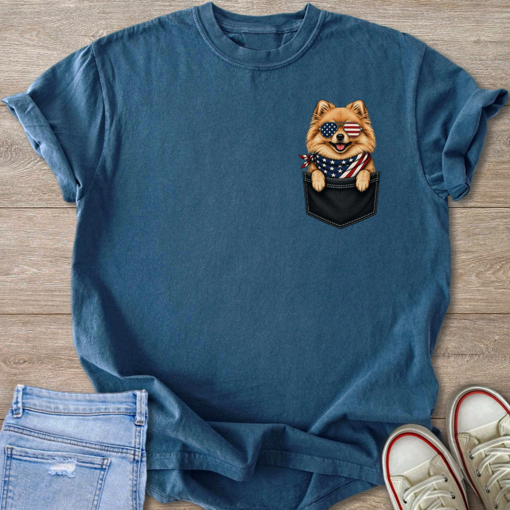 Pomeranian dog in pocket with American flag bandana and sunglasses graphic on t-shirt.