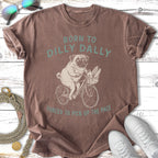 Brown t-shirt with pug on bicycle and text "BORN TO DILLY DALLY FORCED TO PICK UP THE PACE".