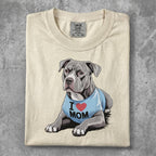 Pit bull wearing a blue "I MOM" t-shirt, lying down.