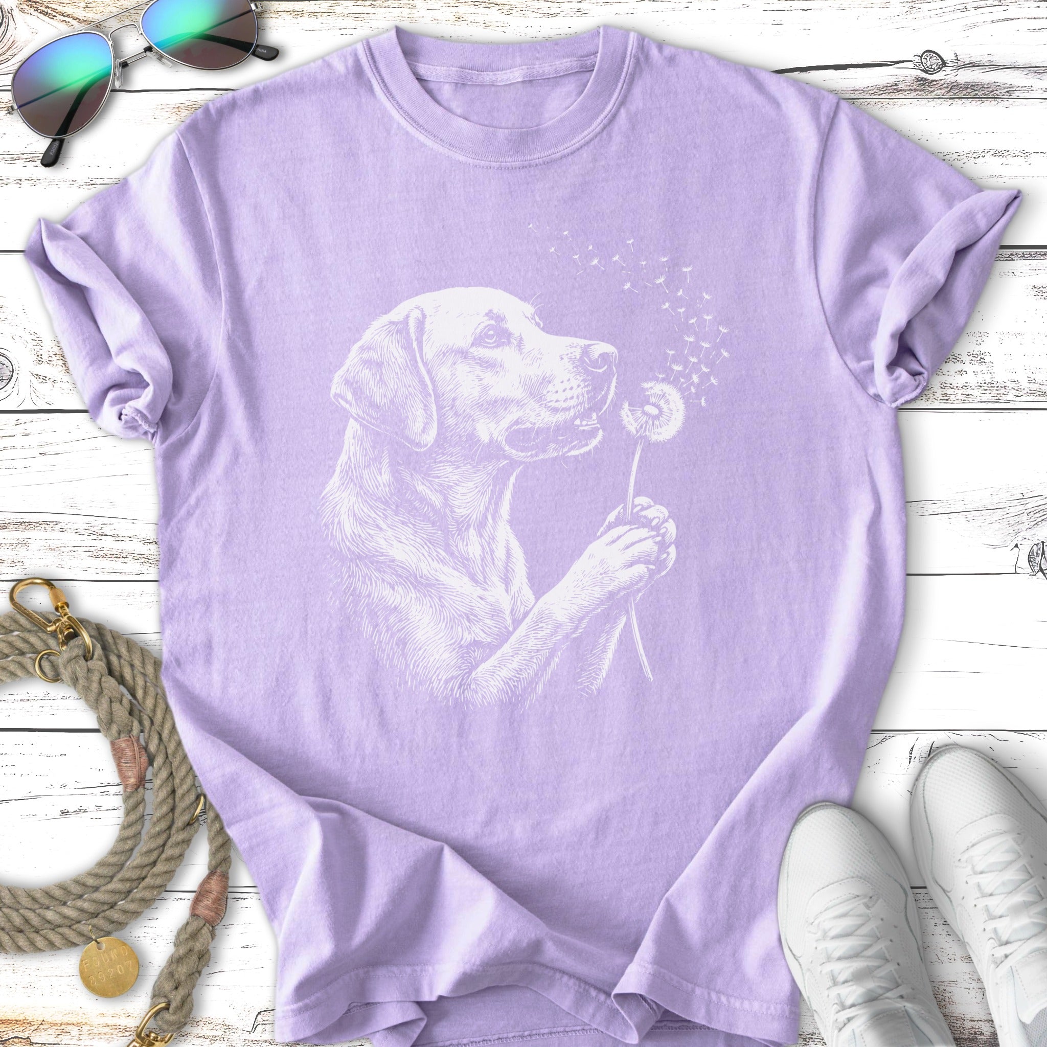 Lavender t-shirt with white line art of a dog holding a dandelion.