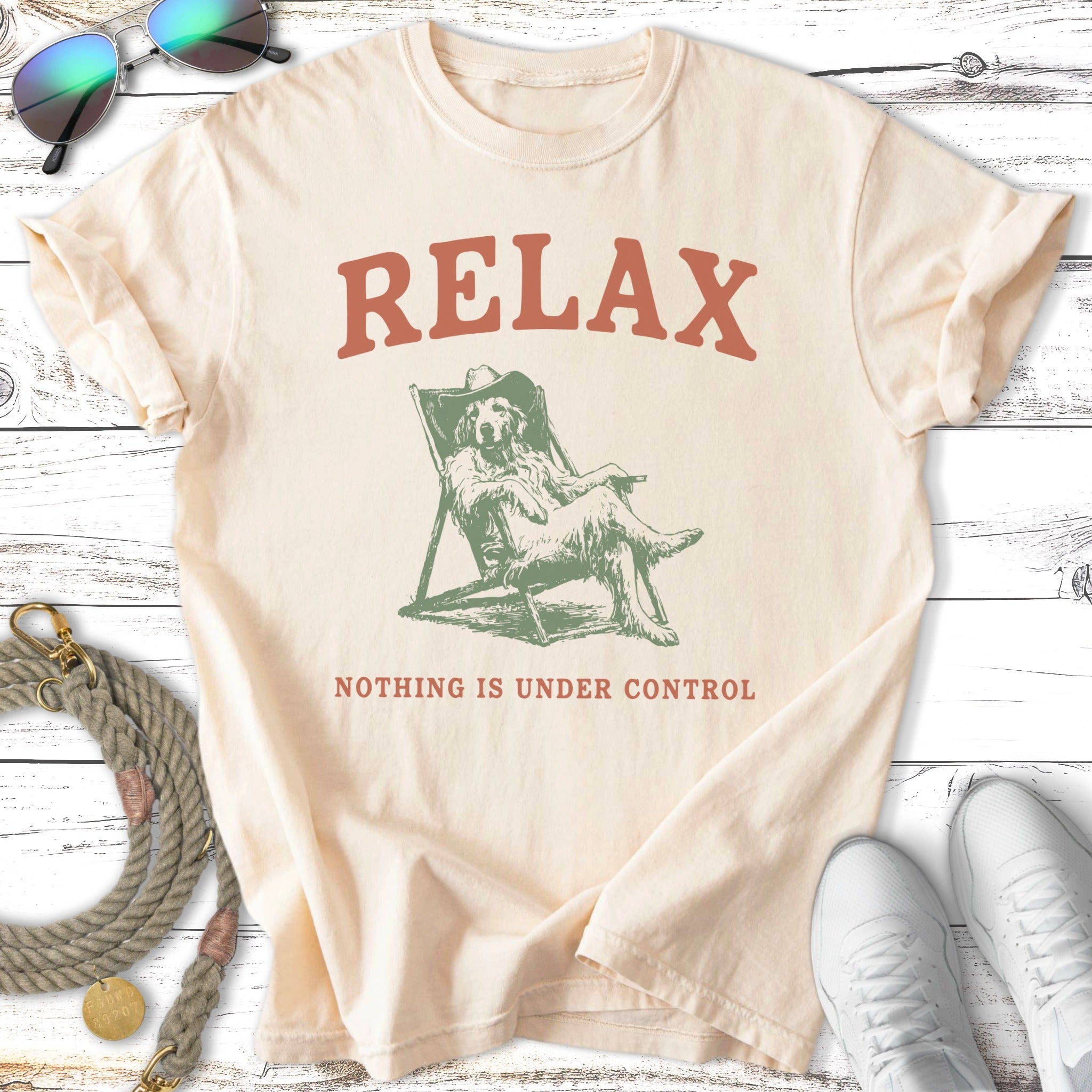 Cream t-shirt with dog lounging in chair, "RELAX NOTHING IS UNDER CONTROL" text.