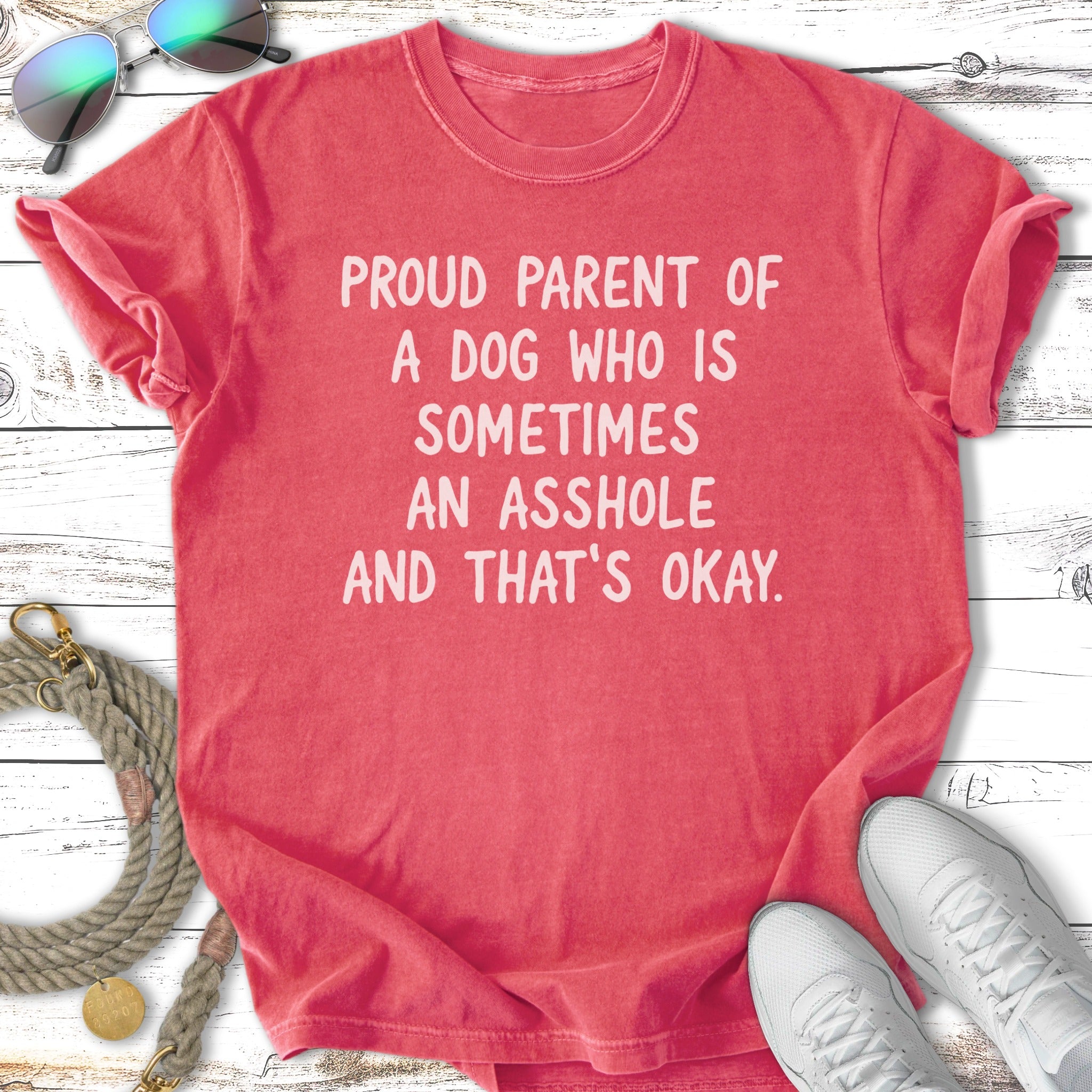 Red t-shirt with white text reading "Proud parent of a dog who is sometimes an asshole and that's okay."