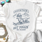 White t-shirt with dachshund in sunglasses and hat on skis, "Mountain Hot Doggin' Ski Resort" text.
