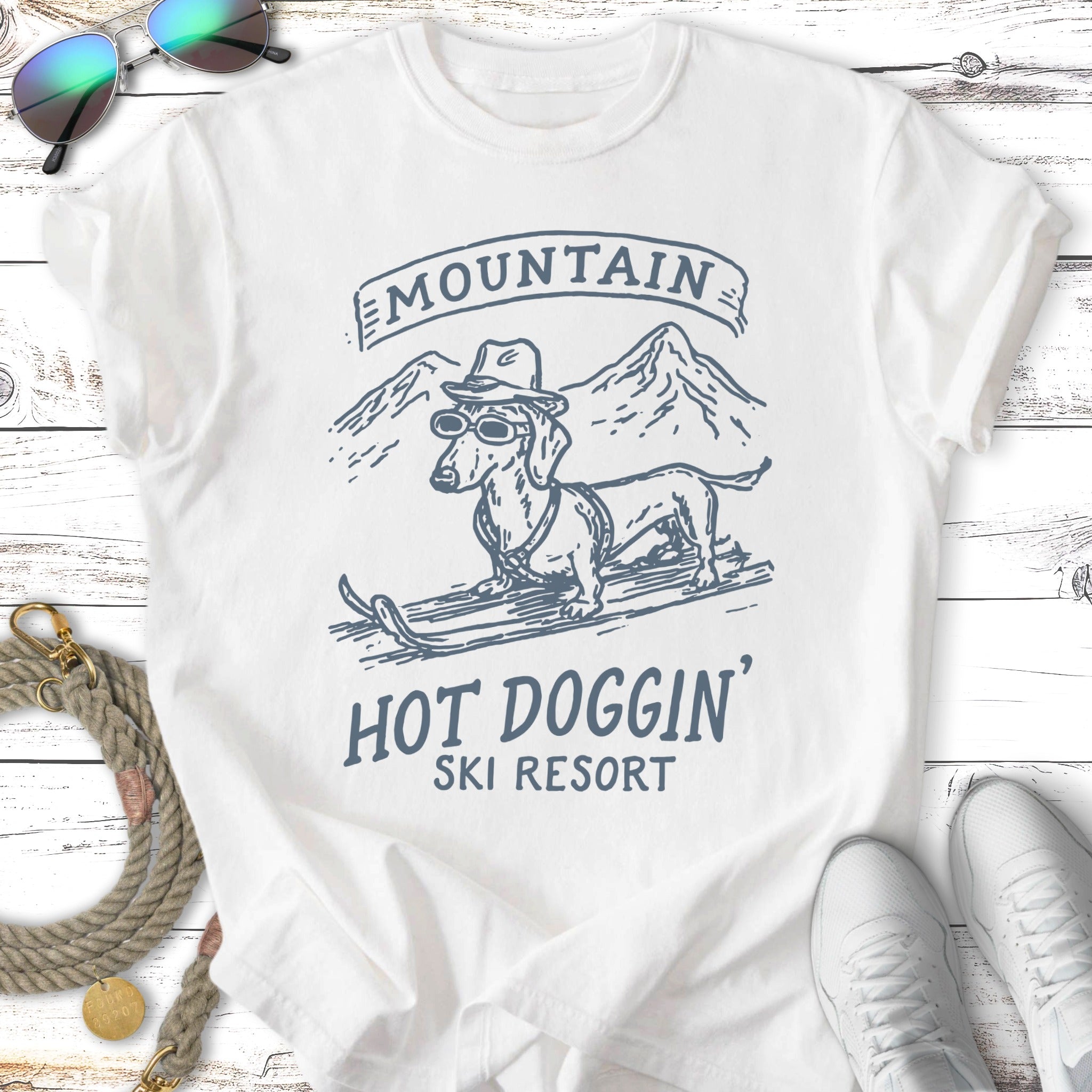 White t-shirt with dachshund in sunglasses and hat on skis, "Mountain Hot Doggin' Ski Resort" text.