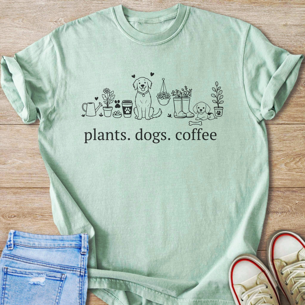 Light green t-shirt with line art of plants, dogs, coffee cups, and boots.