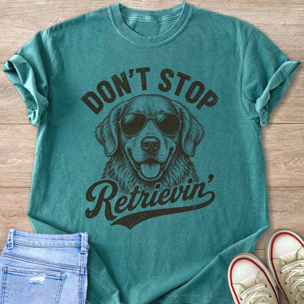 Teal t-shirt with a drawing of a golden retriever wearing sunglasses and text that says "Don't Stop Retrieving".