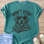 Teal t-shirt with a drawing of a golden retriever wearing sunglasses and text that says "Don't Stop Retrieving".