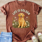 Golden retriever sits in a field of daisies with text "LIFE IS GOLDEN" above.