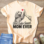 Light peach t-shirt with a drawing of a Cocker Spaniel giving a high-five, text says "Best Cocker Spaniel MOM EVER".