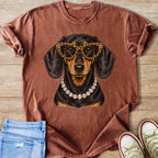 Dachshund wearing leopard glasses and diamond necklace graphic on rust t-shirt.