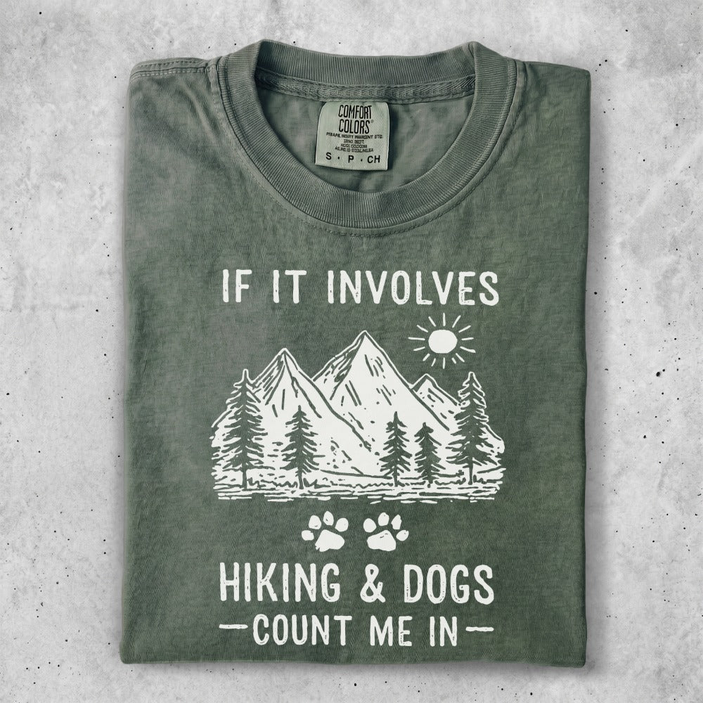T-shirt with mountains, trees, and text "IF IT INVOLVES HIKING & DOGS - COUNT ME IN-".