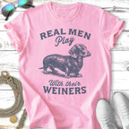 Pink t-shirt with illustration of a dachshund and text "REAL MEN Play With their WEINERS".
