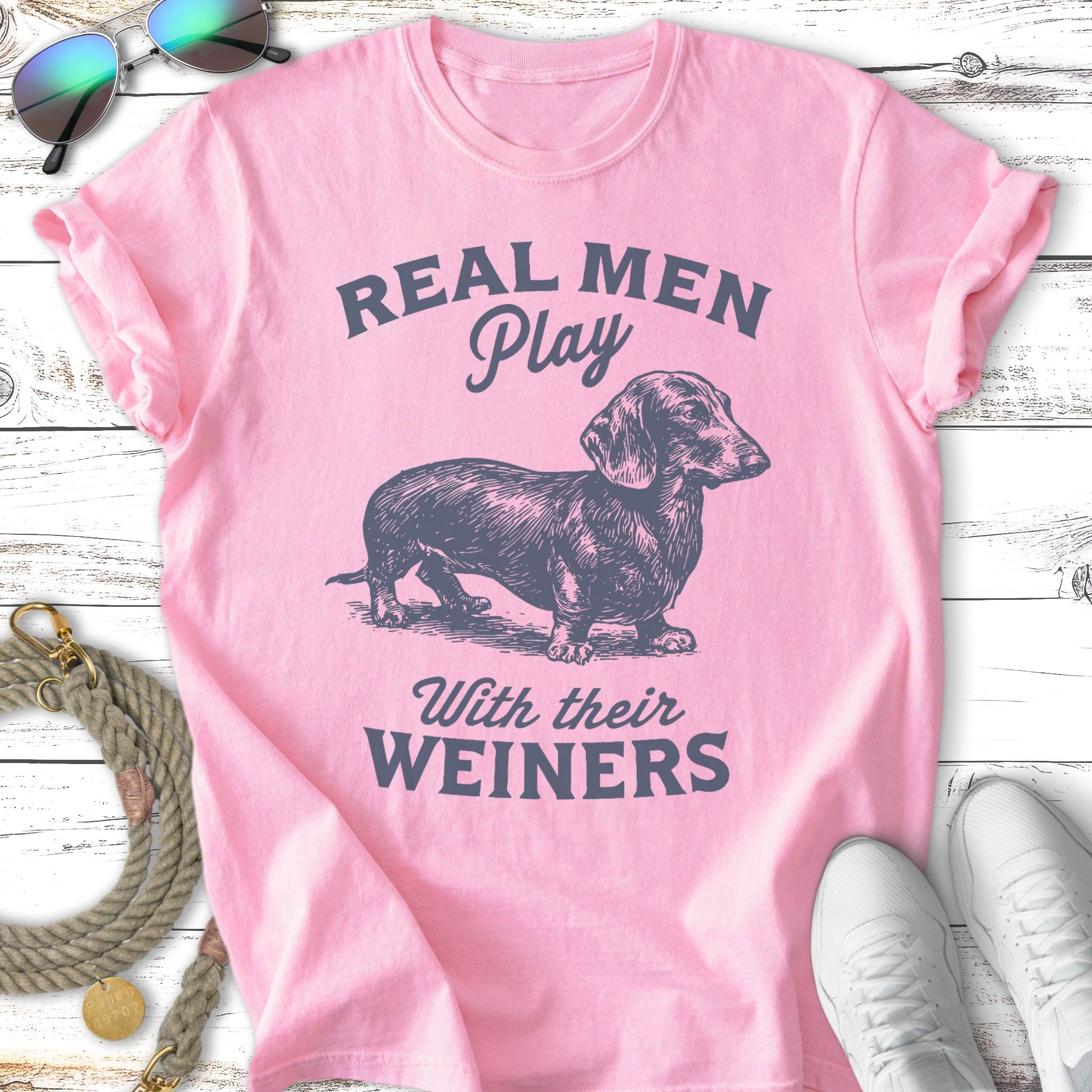 Pink t-shirt with illustration of a dachshund and text "REAL MEN Play With their WEINERS".