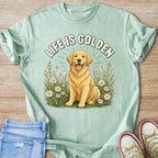 Golden Retriever with "LIFE IS GOLDEN" text among daisies on a light green t-shirt.