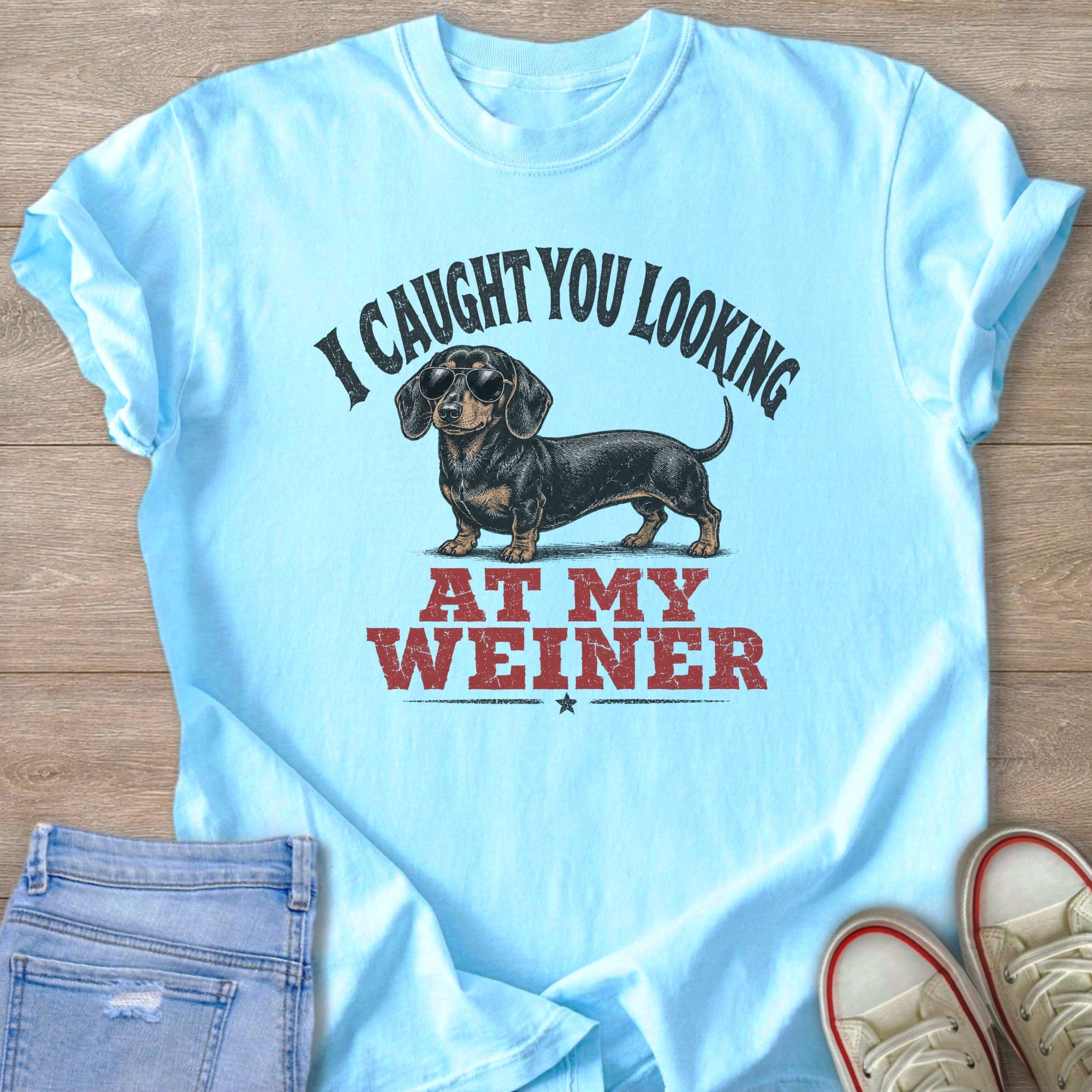 Light blue t-shirt with a dachshund wearing sunglasses and text "I CAUGHT YOU LOOKING AT MY WEINER".