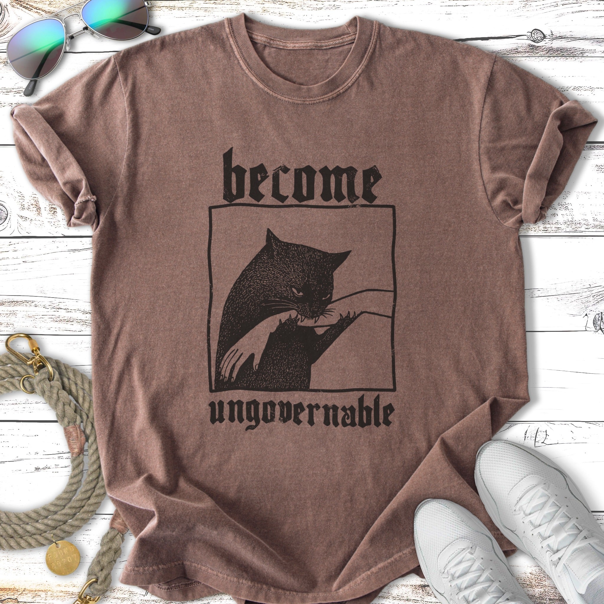 Brown t-shirt with black graphic of a cat and text "become ungovernable".