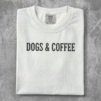 White t-shirt with "DOGS & COFFEE" text printed in black.