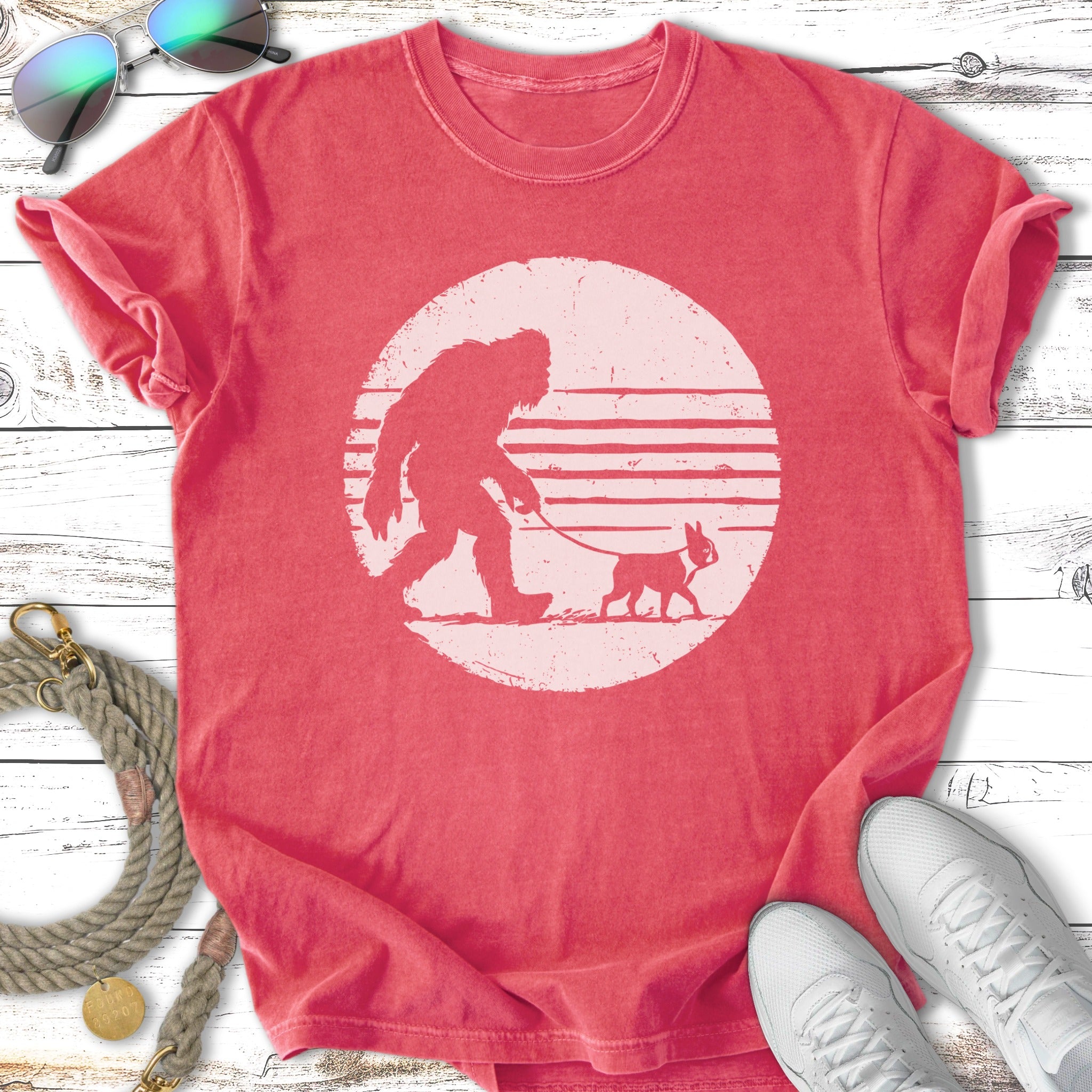 Bigfoot walking a dog with a distressed sun graphic.