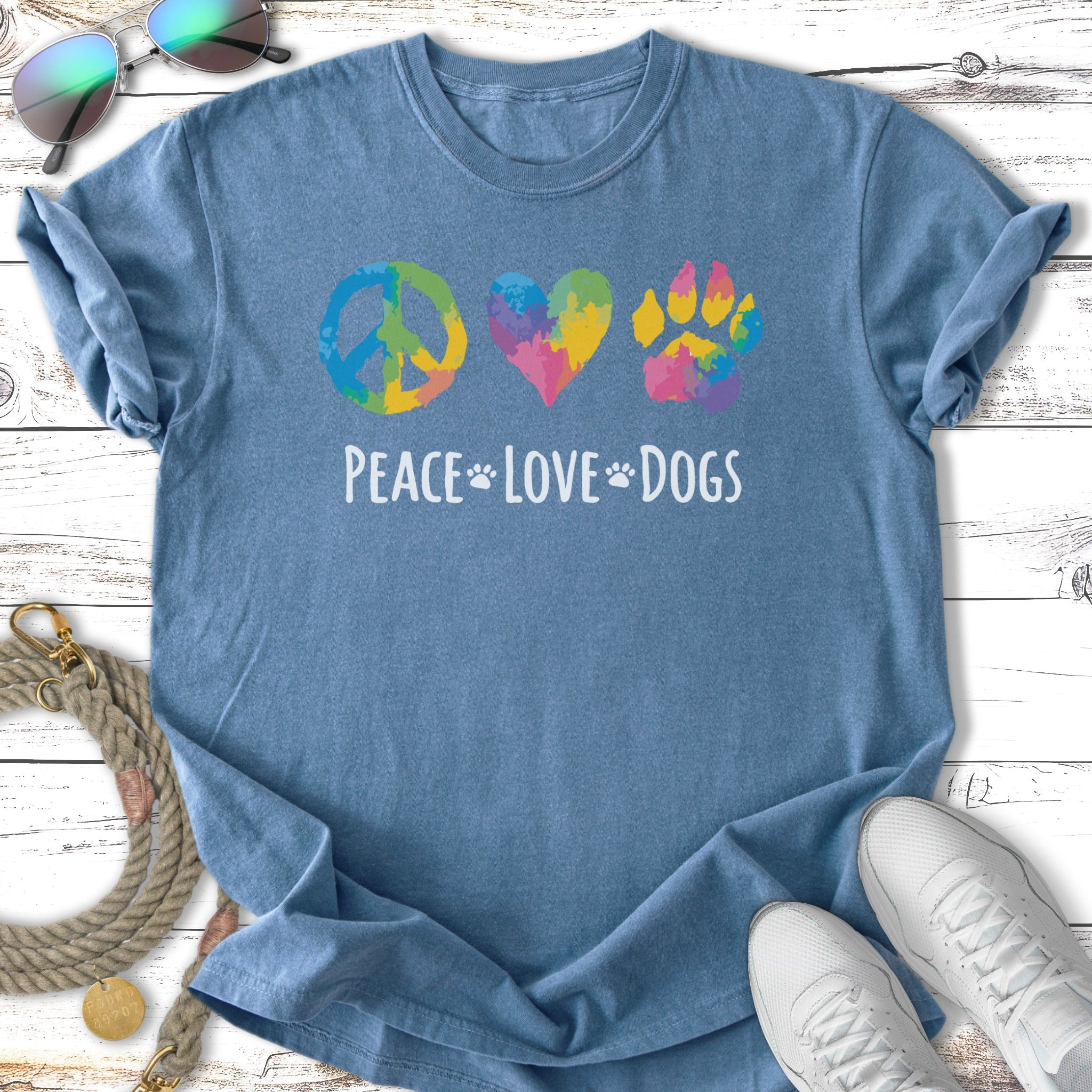Blue t-shirt with colorful peace sign, heart, and paw print graphic and text.