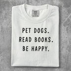 White t-shirt with "Pet dogs. Read books. Be happy." text.