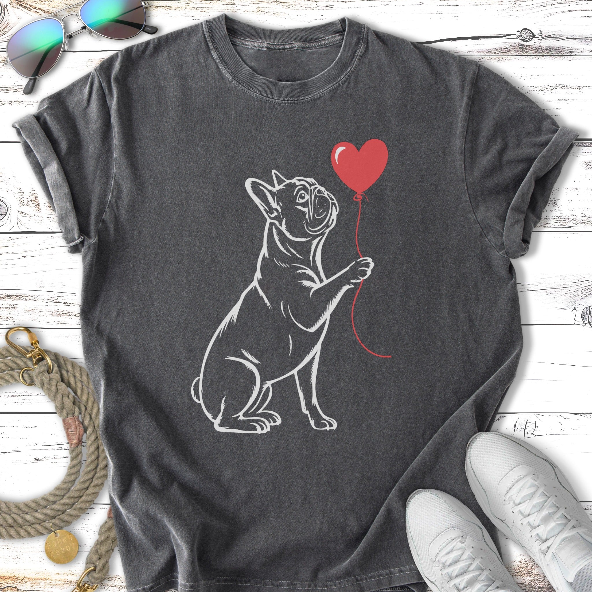 French bulldog holding a red balloon in its paw.
