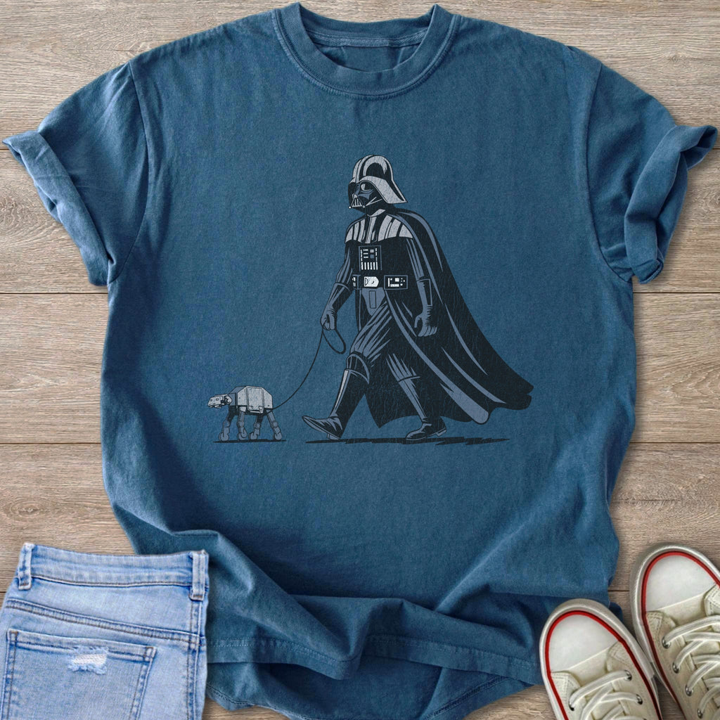 Darth Vader walking a small AT-ST walker on a leash on a blue t-shirt.