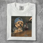 Yorkshire terrier in a cap being poured red wine into a glass.