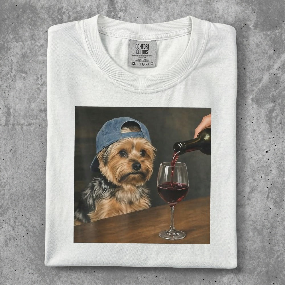 Yorkshire terrier in a cap being poured red wine into a glass.
