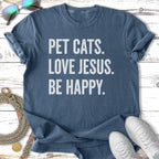 Blue t-shirt with white text reading "PET CATS. LOVE JESUS. BE HAPPY."