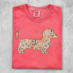 Coral t-shirt with a dachshund silhouette filled with floral pattern.