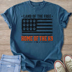 Blue t-shirt with American flag design and paw prints, says "Land of the Free Home of the K9".