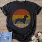 Black t-shirt with a dark dachshund silhouette on a vintage striped circle background.