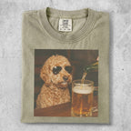 Goldendoodle in sunglasses gets a beer poured in a mug.